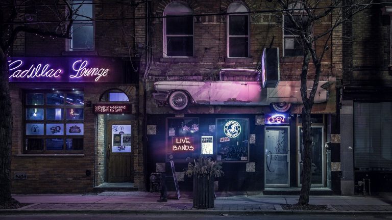 a building with a neon sign and a car parked in front of it.