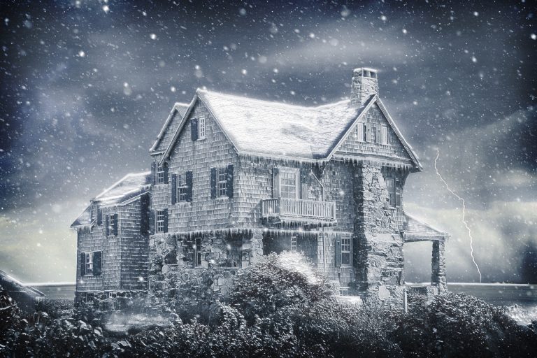 an old house with snow falling from the roof.