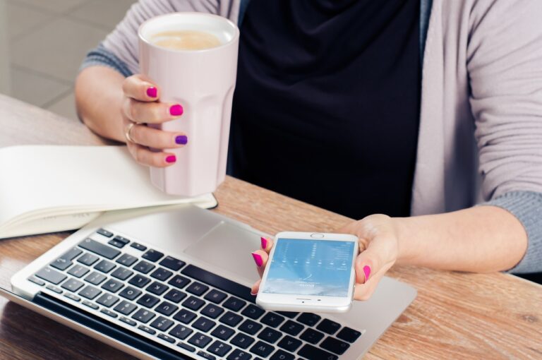 a woman holding a cup of coffee and a cell phone.